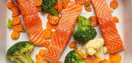 Top view of baking dish casserole with raw uncooked fish salmon steaks, broccoli, cauliflower,