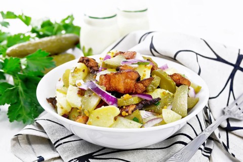 Salad of boiled potatoes, fried bacon, red onions and pickled cucumbers, seasoned with grain