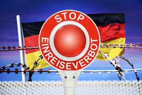 Police trowel with the inscription Stop Entry Ban in front of the German flag and barbed wire,