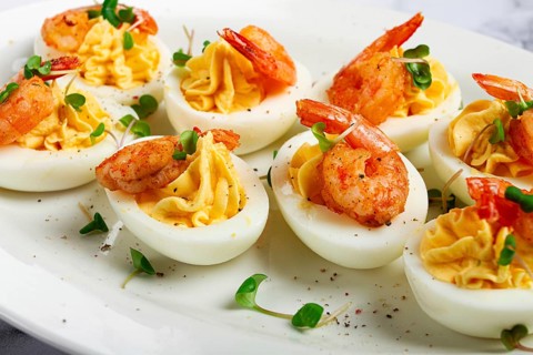Boiled eggs stuffed with yolk and seasoned with mayonnaise, stuffed eggs with shrimp, on a white