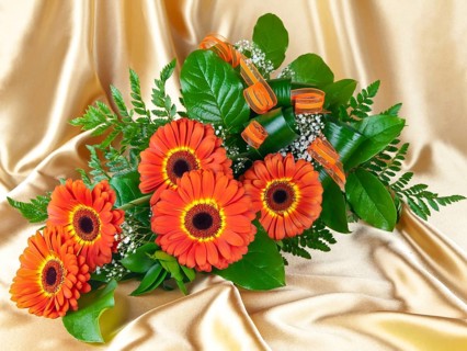 Bouquet of gerberas with green leaves over golden background