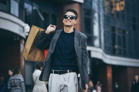 Serious cool guy with sunglasses and paper bags walking at street