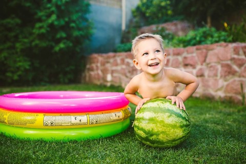 Toddler cute Caucasian white European race boy sitting hugging holding huge watermelon and smiling