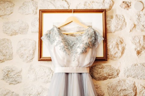 White wedding dress of the bride with patterns on a hanger on the picture frame.
