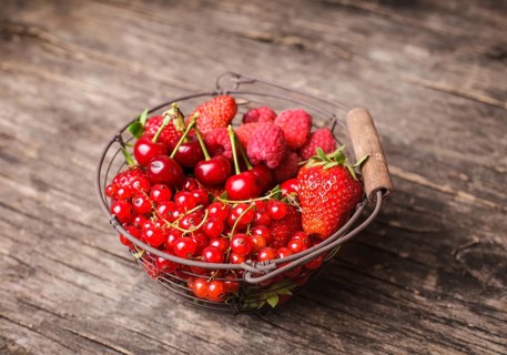 Red summer fruits in metal basket on the table