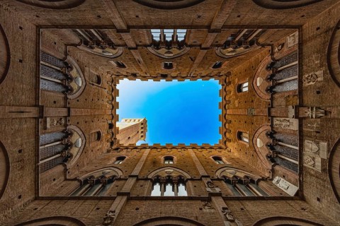 View into the sky of the Torre del Mangia, through a historic courtyard, Palazzo Pubblico, Siena,