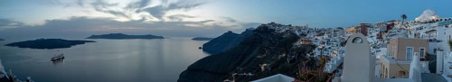 Cruise ship in the archipelago of Santorini, evening mood after sunset, white buildings at the edge