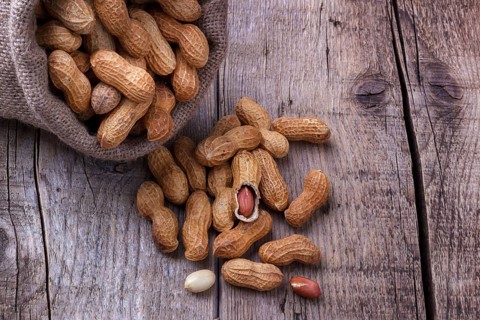 Peanuts in a burlap sack on wooden background