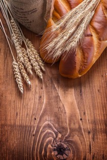 Bguettes and wheat ears on vintage wooden board with copyspace food and drink concept