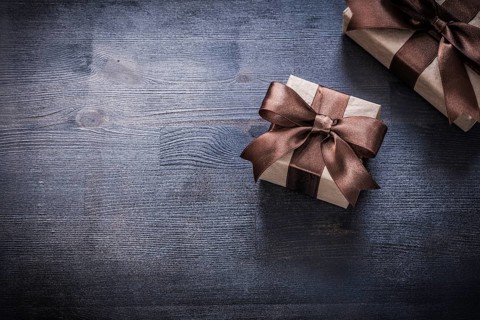 Gift containers with tied ribbons on wood board holiday concept