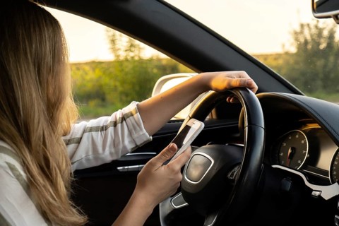 Womandriver using mobile phone paying for parking and navigating in the city while stopped on the