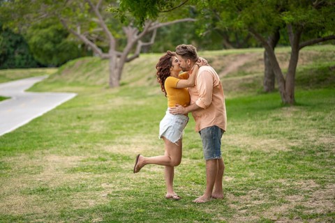 Couple kisses while walking through the park