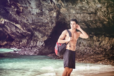 Half body shot of a handsome young man standing on a beach in Phuket Island, Thailand, shirtless