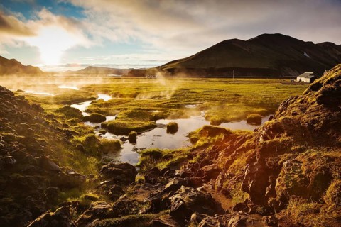 Above the source of thermal water steam rises. White nights in Iceland. Sunrise Park
