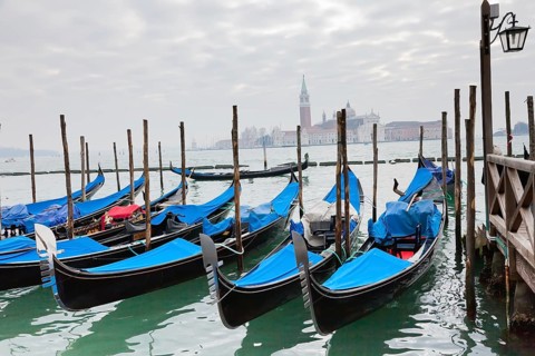 Gondolas with blue cover in Venice at the pier