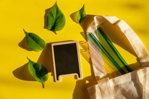 Reusable glass Straws on colorful background with green leafs in eco bag Eco-Friendly. Empty