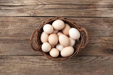 Organic chicken eggs in basket on wooden background. Organic household concept with eggs from