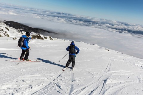 Two skiers are at the top of a peak of Vitosha mountain. They are participating in an freestyle