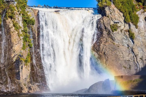 Magnificent rainbow in the spray of the waterfall Montmorency in Montmorency Falls Park. Above the