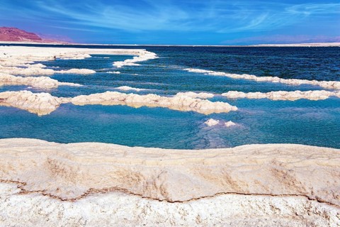 The evaporated salt forms bizarre patterns on the surface of the water. Cirrus clouds fly in the