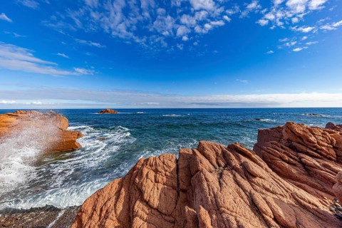 Coastal landscape with red rocks and surf in blue sky and sunshine, Spiaggia di Cala E'Luas,