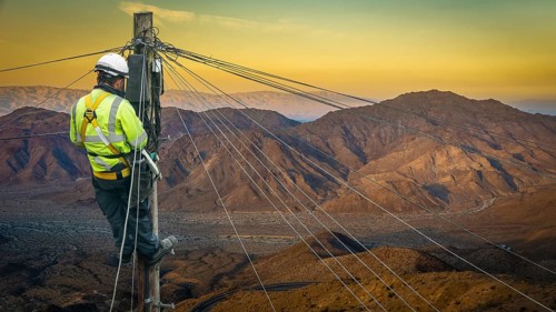 Lineman (Or Lineworker or Engineer) In A Remote Desert Landscape Fixing A Telephone Line