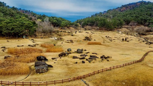 Gochang, South Korea. Dec. 4, 2024. Aerial view of dolmen tomb site with mountains and blue cloudy