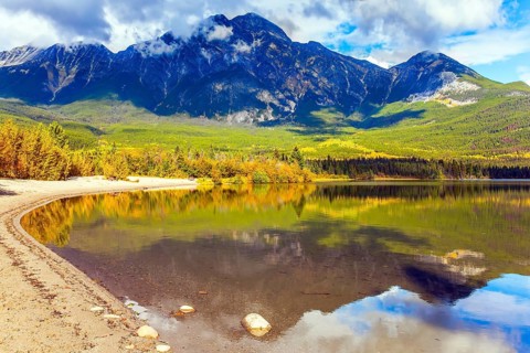 Rocky Mountains of Canada. Smooth water of the lake reflects Pyramid Mountain and lush cumulus