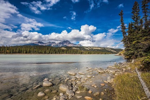 Evergreen forests and snow-capped Rocky Mountains of Canada. Beneaped Medicine Lake in the fall
