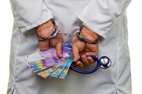 A doctor with Swiss franc banknotes and handcuffs, Austria, Europe