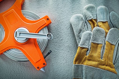 Set of protective gloves measuring tape on concrete background