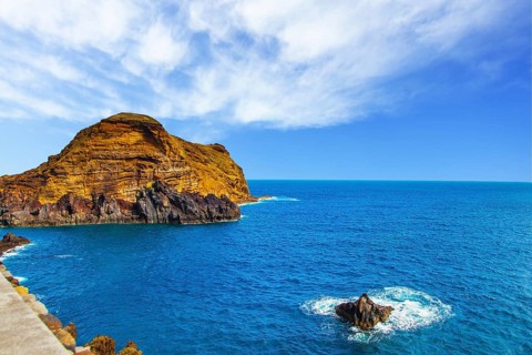 Calm bay with azure water. Rocks and stones off the shores of the volcanic island of Madeira. The