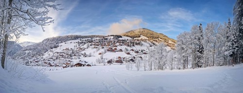 Panoramic winter scene of snow covered La Clusaz village nestled in a hilly landscape in Annecy,