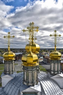 Golden domes of the Holy Trinity Cathedral in the background of the city, blue sky and white clouds