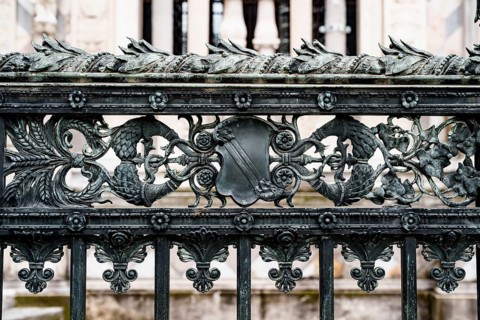 Antique wrought iron fence near the Duomo Cathedral in Milan with spikelets, shields, flowers and