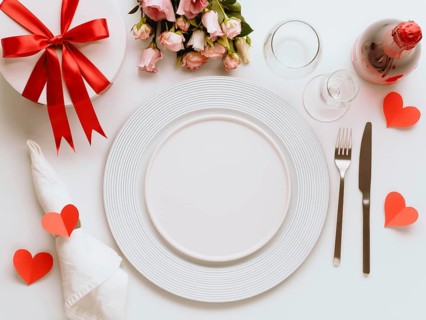 Valentines Day tablesettings concept on white background. Empty white plates, gold cutlery, rose