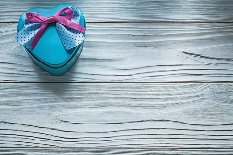Heart-shaped blue present box with pink bow on wooden board holidays concept
