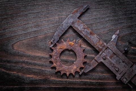 Rusty retro-styled measuring calipers with pinion gear on vintage dark wooden background