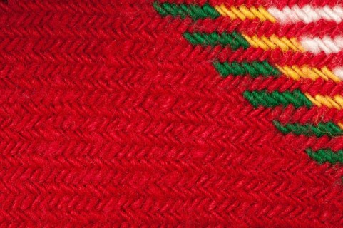 Handmade knit green and red background. Close up structure of the yarn. Christmas colors