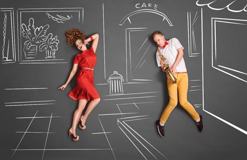 Love story concept of a romantic couple against chalk drawings background. Male playing the