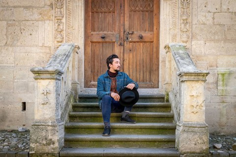 Portrait of a young man sitting against a beautiful old medieval cathedral door. A man in front of