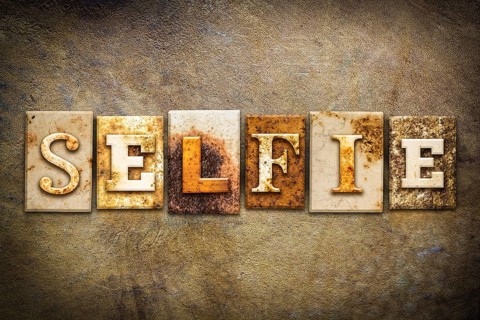 The word SELFIE written in rusty metal letterpress type on an old aged leather background
