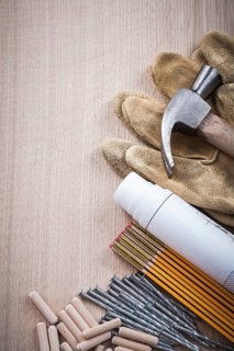 Wooden meter dowels construction plans claw hammer pair of safety gloves and nails on wood board