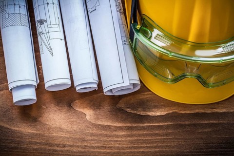 Goggles construction plans and hard hat on brown wood board