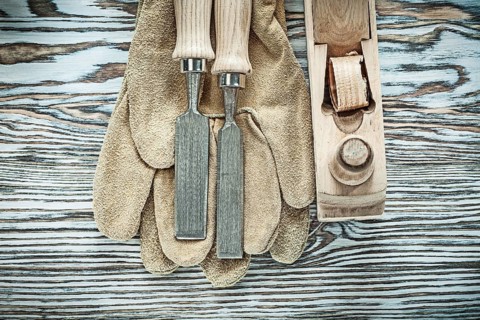 Protective gloves flat chisels planer on wooden board