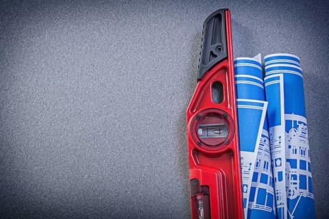 Construction level blue rolled blueprints on grey background copy space maintenance concept