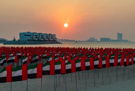 A picture of many United Arab Emirates flags at the Jumeirah Public Beach, at sunset