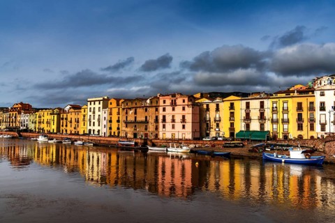 Bosa, Italy, 13 December, 2022: colorful houses and fishing boats on the waterfront of Bosa on the
