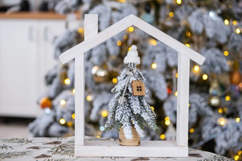 Key on Christmas tree and tiny house on cozy home with Christmas decor on table of festive white