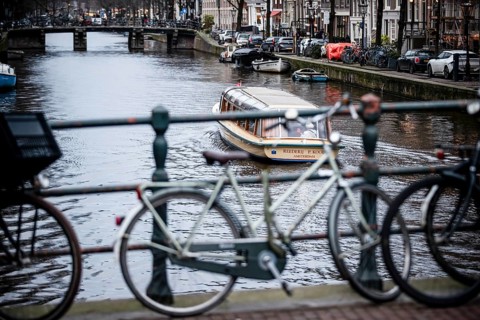 A canal tour boat navigates the web of canals in the central region of the city of Amsterdam, The